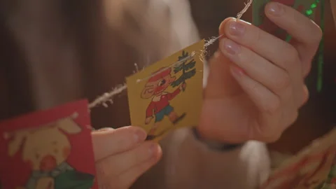 Intimate closeup hands stringing vintage cards, soft warm light, twine and Stock Footage 346547245
