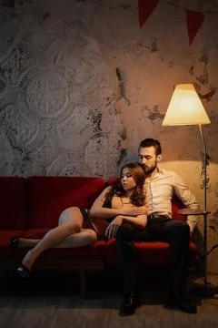 Intimate connection between couple relaxing on a cozy couch in a softly lit room Stock Photos