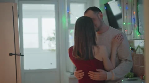 Intimate couple embracing in cozy kitchen with warm natural window light Stock Footage 346644859