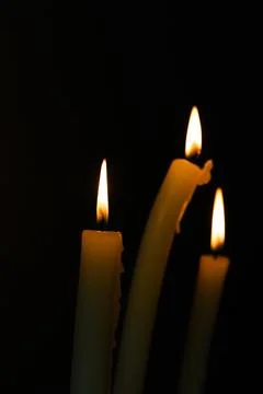 An Intimate Glimpse into the Flickering Flames of Three Candles in a Dark Stock Photos