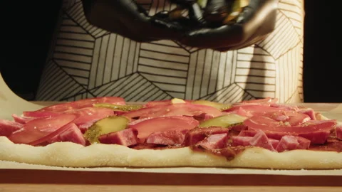 Intimate kitchen scene with hands adding slices of cucumber to pizza dough Stock Footage 331849418