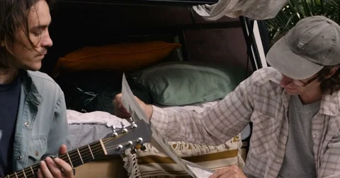 Intimate moment between two male friends camping and looking at a map Stock Footage 80809428