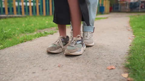 Intimate moment of couple exchanging subtle foot signals in park, Close up of Stock Footage 327731705