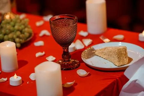 Intimate red table setting with textured glass, cake slice, candles, and fr.. Stock Photos