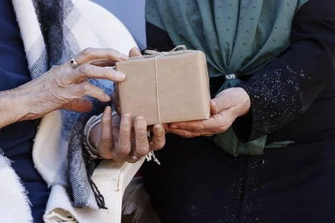 An intimate scene of two elderly people sharing a wrapped gift. Warmth and gener Stock Photos
