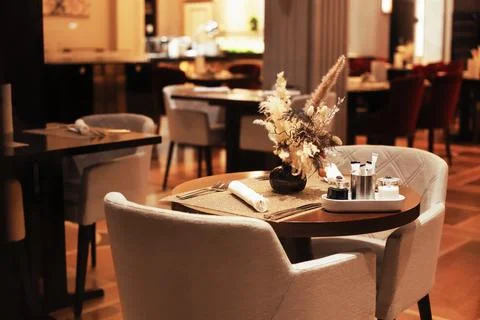 An intimate table setting in a luxury restaurant with a floral centerpiece,.. Stock Photos