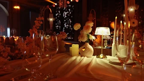Intimate upscale dining table with sculptural vase, candles, and textured lamp Stock Footage 346083355