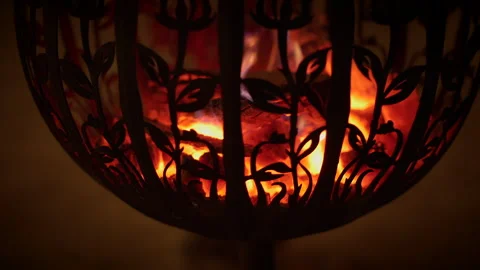 An intricate fire pit creates a warm glow with embers, providing a cozy Stock Footage 280681045