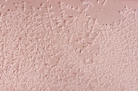 Intricate ice crystals create a delicate frosty pattern on a rosy pink surf.. Stock Photos