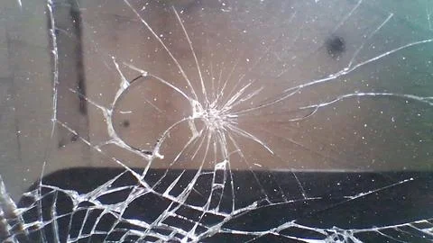 Intricate pattern of shattered glass surface with sharp radial cracks Foto stock