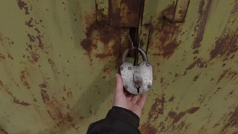The intricate process of unlocking a rusty padlock secured on a weathered green Stock Footage 309883741
