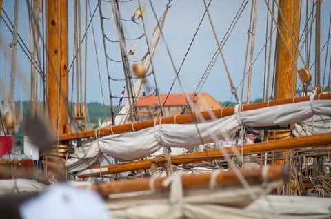 Intricate rigging on sailing ship with harbor buildings in the background. Stock Photos