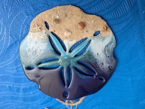 Intricate shell art featuring a transparent starfish cutout over a beach Stock Photos