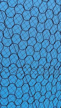 Intricate wire mesh fence pattern against blue sky. Stock Photos