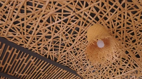 Intricate woven bamboo ceiling design with a hanging lamp fixture. Video stock 343376377