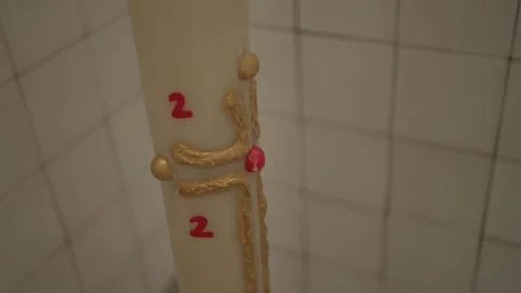 Intricately decorated Easter candle with red and gold detailing on a tiled Stock Footage 281309214