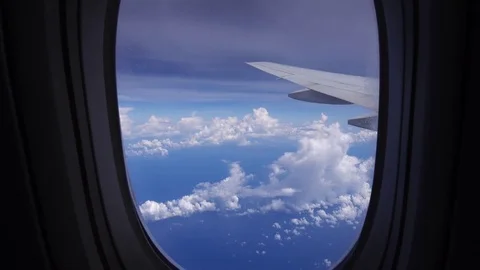 Intriguing view through aircraft window on cloudscape and airplane wing. 4K Stock Footage 70360727