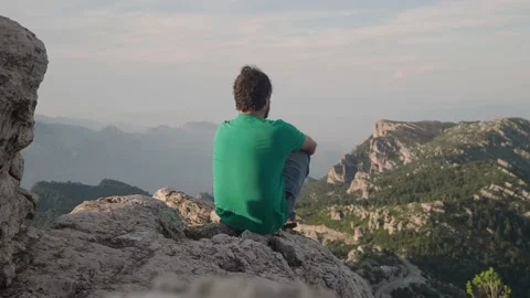 Introspective adventurous man sitting on top of the mountain Stock Footage 159475073