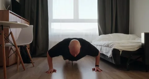 An introverted single man does sports at home, push-ups on the bedroom floor Stock Footage 302901266