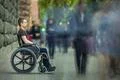 The invalid man sit in the wheel chair in the crowd stream at sidewalk Photo