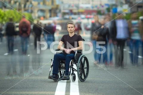 The invalid man sit in the wheel chair in the crowd stream at the road Stock Photos