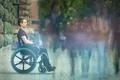 The invalid man sit in the wheel chair in the crowd stream at sidewalk Photo