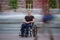 The invalid man sit in the wheel chair in the crowd stream at the pavement Photo
