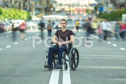 The invalid man sit in the wheel chair in the crowd stream at the road Stock Photos