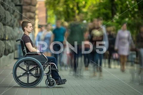 The invalid man sit in the wheel chair in the crowd stream at sidewalk Stock Photos
