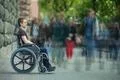 The invalid man sit in the wheel chair in the crowd stream at sidewalk Photo