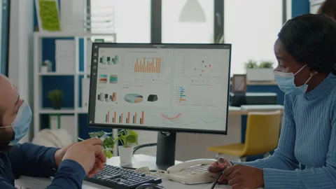 Invalid manager with face mask explaning to black employee financial evolution Vídeos de archivo 154229103