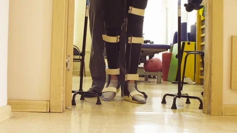 Invalid in orthosis walking with support of two walking cane Stock Footage 95288664