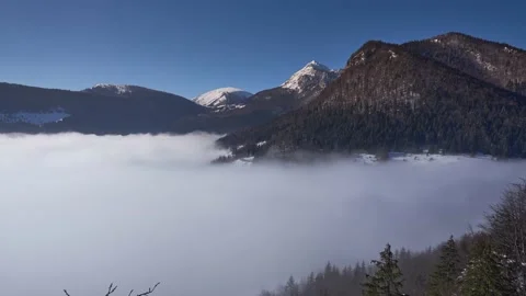 Inverse clouds moving fast in the valley below the mountain ridges in winter Stock Footage 150026283