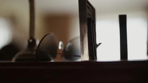 Inverted sunglasses with thin metal frames sit on top of wooden shelf. Close-up Stock Footage 154503147