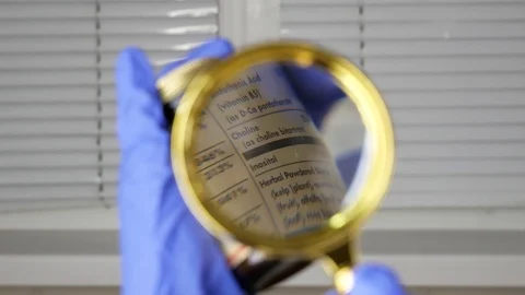 Investigating ingredients of medicines using magnifying glass, gloved hand Stock Footage 126990334