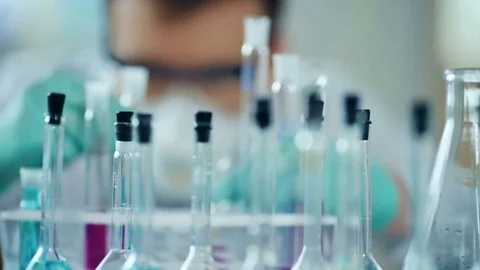 Investigator checking test tubes. Man wears protective goggles and mask Видео 85328739
