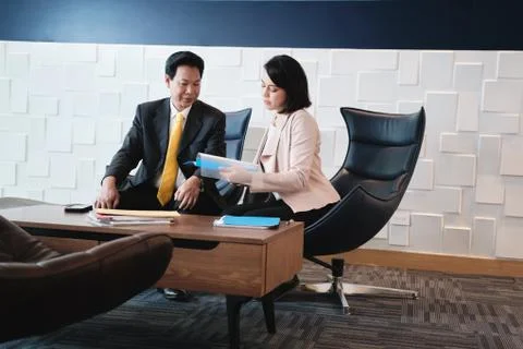 Investment Plan Agent Showing Documents To Asian Customer In Bank Stock Photos