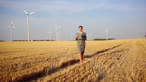 Investor in wind turbines with computer evaluating her investment on site Stock Footage 101603799
