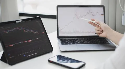 Investors sit and watch graphs of stock market data and watch the world marke Stock Photos