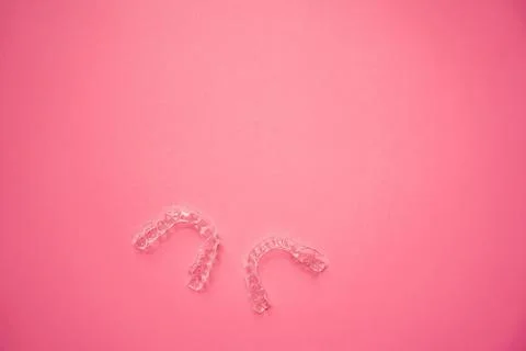 Invisalign braces or invisible retainer on pink background Stock Photos