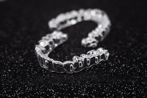 Invisible aligner teeth retainers on a black background. Plastic braces denti Stock Photos