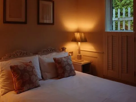 Inviting bedroom interior featuring a comfortable bed, warm lamp lighting, .. Stock Photos