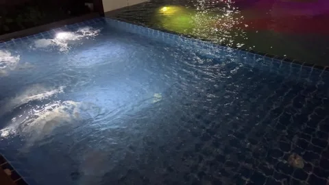 Inviting blue mosaic tiled pool with steps on a dark night. The calming water Stock Footage 316260893