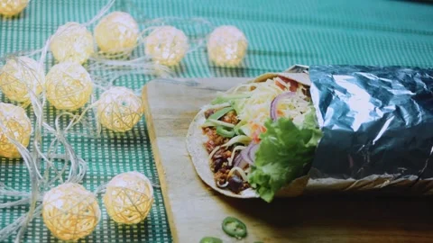 Inviting ingredient view: serving a foil-wrapped burrito on a rustic table Stock Footage 342168244