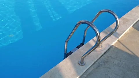 Inviting pool ladder reflecting in clear blue water Stock-Footage 312122389