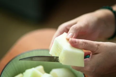 This inviting scene, a pair of delicate hands deftly slice a ripe melon, reve Stock Photos