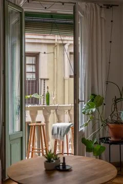 Inviting small balcony setup with stools, a table, and a wine bottle creating a Stock Photos