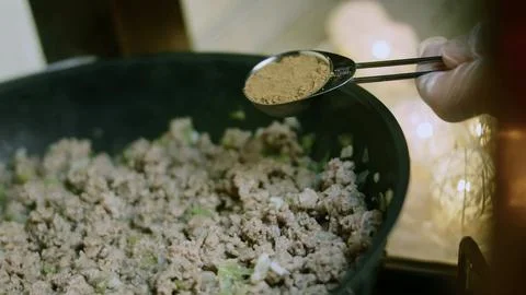 Inviting tabletop view of adding dried herbs to cooked ground beef Stock Photos