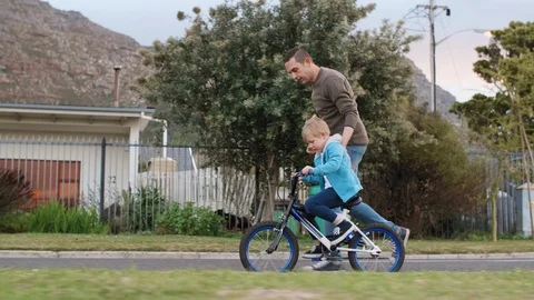 Involved dad teaching how to ride a bike Stock Footage 120356696