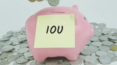 IOU Word Or Text on Yellow Note Paper and Hand Inserting Coins to Pink Piggy Stock Footage 301514540